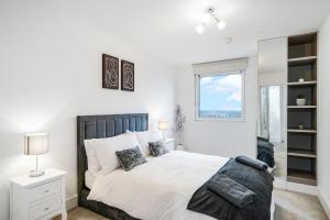 a white bedroom with a bed and a window at Luxury Apartment With Stunning Views on 10th floor in Edgware
