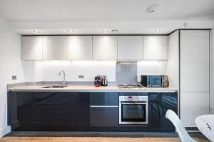 a kitchen with black and white cabinets and a sink at Luxury Apartment With Stunning Views on 10th floor in Edgware