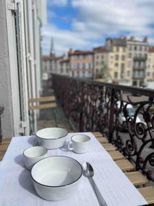 une table avec des bols et des cuillères sur un balcon dans l'établissement Appartement hyper centre avec balcon, à Clermont-Ferrand