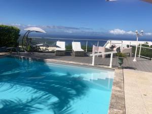 a swimming pool with chairs and a view of the ocean at Entre ciel et mer piscine chauffée in Saint-Leu