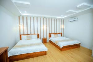 um quarto com 2 camas e piso em madeira em khách sạn Quốc Tế em Cà Mau