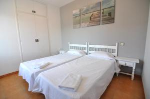 een witte slaapkamer met 2 bedden en witte lakens bij RNET - MTA Apartaments A3 in Roses +13 foto's