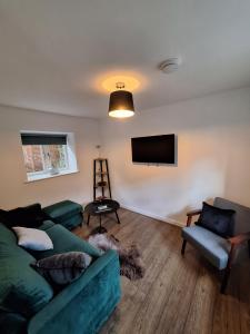 ein Wohnzimmer mit einem grünen Sofa und einem Flachbild-TV in der Unterkunft Mount Cottage in Shrewsbury