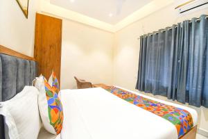 1 dormitorio con cama blanca y cortinas azules en FabHotel Prime The Golden Plaza, en Tarapith