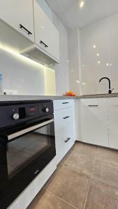 una cocina con horno negro y armarios blancos en Atlantico Flamingo, en Calpe