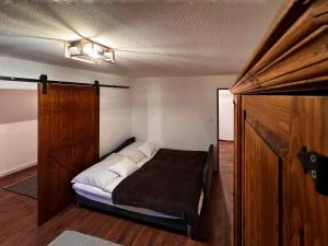 1 dormitorio con 1 cama y puerta de madera en Pilisi Lovas Major, Dorog, en Dorog