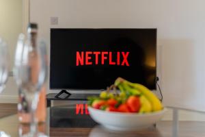 a bowl of fruit on a table in front of a television at Contractor Accommodation Specialist, 3 bedroom house with FREE Parking, Wifi & Netflix! in Milton Keynes