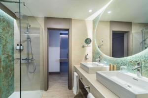 a bathroom with two sinks and a shower and a mirror at Occidental Puerto Banús in Marbella