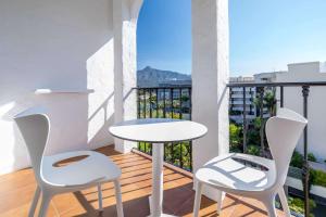 uma varanda com uma mesa branca e 2 cadeiras em Occidental Puerto Banús em Marbella