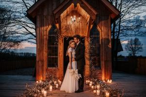 a bride and groom standing in front of a gazebo with candles at OSADA LEŚNA - domki z basenem in Stare Miasto +68 photos