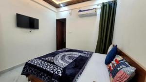 a bedroom with a bed and a flat screen tv at Goroomgo YP Stays Dehradun - Parking facilities - Best Seller in Dehradun