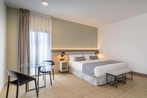 a bedroom with a bed and a glass table at Occidental Puerto Banús in Marbella