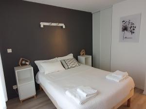 sypialnia z białym łóżkiem i 2 ręcznikami w obiekcie GITE LES ARCHES w mieście Saint-Andéol-le-Château