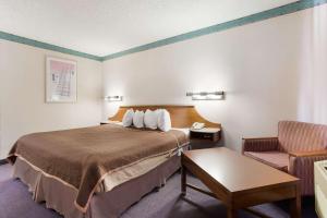 a hotel room with a bed and a chair at Rodeway Inn in Gallup