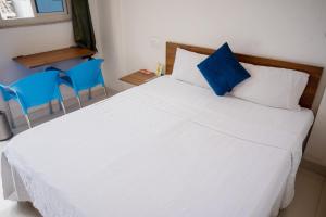 a bedroom with a white bed and two blue chairs at Goroomgo YP Stays Dehradun - Parking facilities - Best Seller in Dehradun