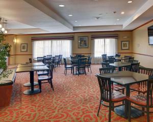 a dining room with tables and chairs and windows at Quality Suites Near Cedar Creek Lake in Mabank