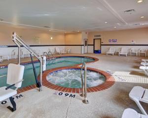 a large pool in a room with chairs and tables at Quality Suites Near Cedar Creek Lake in Mabank