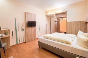 ein Schlafzimmer mit einem Bett und einem Fernseher an der Wand in der Unterkunft Hotel Neumarkt in Berg bei Neumarkt