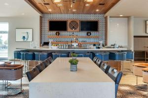 a dining room with a table and chairs and a bar at Cambria Hotel Spokane Airport in Spokane