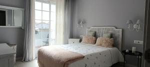 a white bedroom with a white bed with pink pillows at Rincón del Mar Terrazas y vistas a la Ría de Vigo in Moaña