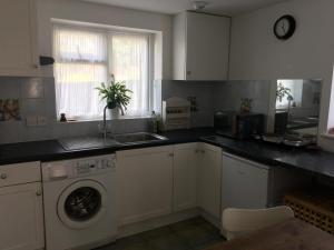 a kitchen with a sink and a washing machine at Barn Corner in Bridport