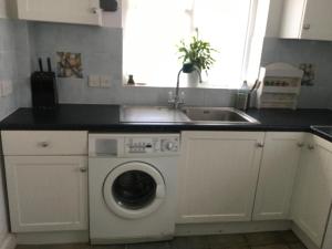 a kitchen with a washing machine and a sink at Barn Corner in Bridport
