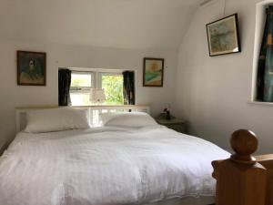 a bedroom with a large white bed with a window at Barn Corner in Bridport