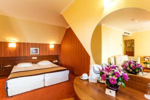 ein Schlafzimmer mit einem Bett und einem Tisch mit Blumen in der Unterkunft Saint George Hotel & Medical Spa in Pomorie