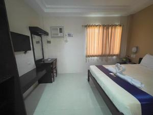 um quarto de hotel com uma cama e uma televisão em Argao Seabreeze Hotel powered by Cocotel em Argao