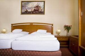 two beds in a room with a painting on the wall at Hotel Saint Antonius in Mariánské Lázně