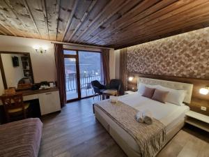 a bedroom with a bed and a desk and a balcony at Семеен Хотел Берое in Stara Zagora