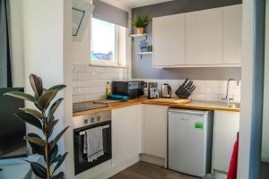 a small kitchen with white cabinets and a refrigerator at Spacious 2BD Maisonette with Lush Loft in Newquay in Newquay