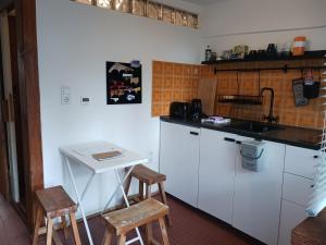 a kitchen with white cabinets and a table and stools at Squat Deluxe Berlin, the hostel in Berlin