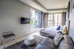 a bedroom with a bed and a couch and a window at The Capital On The Park Luxury Stay in Johannesburg