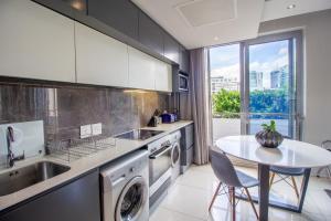 a kitchen with a sink dishwasher and a table at The Capital On The Park Luxury Stay in Johannesburg