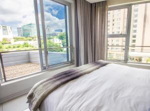 a bedroom with a bed and a large window at The Capital On The Park Luxury Stay in Johannesburg