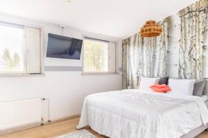 a white bedroom with a bed and a tv at Beautiful Expansive House with Sea views, large private bedrooms available in shared house in Vaasa