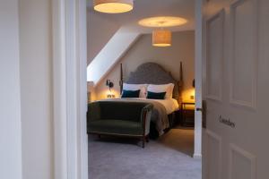a bedroom with a bed and a green chair at Fowey Hall Hotel in Fowey