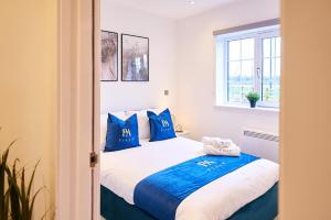 - une chambre avec un grand lit et des oreillers bleus dans l'établissement Midnight Garden fully furnished apt with parking., à Wisbech Saint Mary