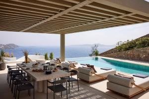 a patio with a table and chairs and a pool at The Coast Bill&Coo-The Leading Hotels of the World in Agios Ioannis Mykonos