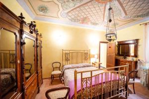 ein Schlafzimmer mit einem Bett, Stühlen und einer Decke in der Unterkunft Degli Alessandri Palace in Sassoferrato