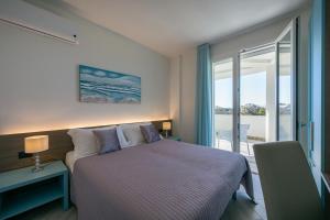 a bedroom with a bed and a large window at Milena Suite Apartments in Alghero