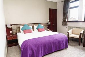 a bedroom with a large bed with a purple blanket at Caladh Inn in Stornoway