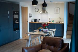 een keuken met blauwe kasten en een tafel met bloemen erop bij Forest Corner Luxury Home with Hot Tub in North Ballachulish