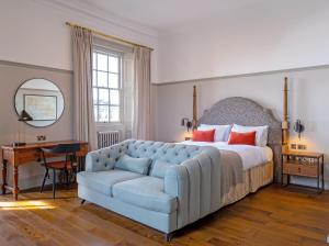 Fowey Hall Hotel في فاوي: غرفة نوم بسرير واريكة زرقاء