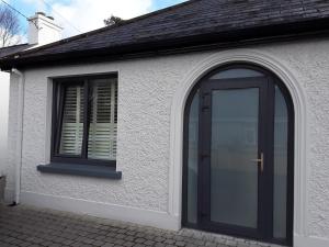 uma casa com uma porta preta e uma janela em Pairc Na Coille Killarney em Killarney