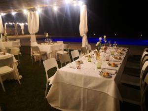 un comedor con mesas blancas, sillas y luces en Agriturismo Masseria Quaremme, en Carpignano Salentino