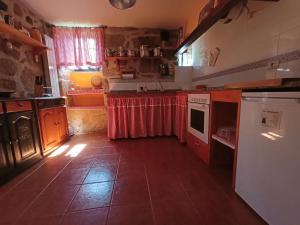 une cuisine avec un rideau rouge sur les comptoirs dans l'établissement Casa Uma Turismo Rural, à Taboeja
