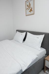 Cozy ApartHotel Suceava في سوسيفا: سرير عليه أغطية ووسائد بيضاء
