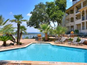 a swimming pool in front of a hotel with palm trees at ILT 3221 Lakeside Serenity in Lago Vista
